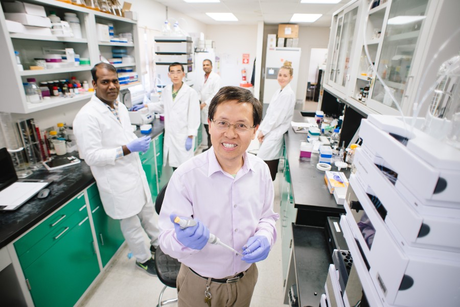 Dr. Shugeng Cao stands in a laboratory with team members behind him