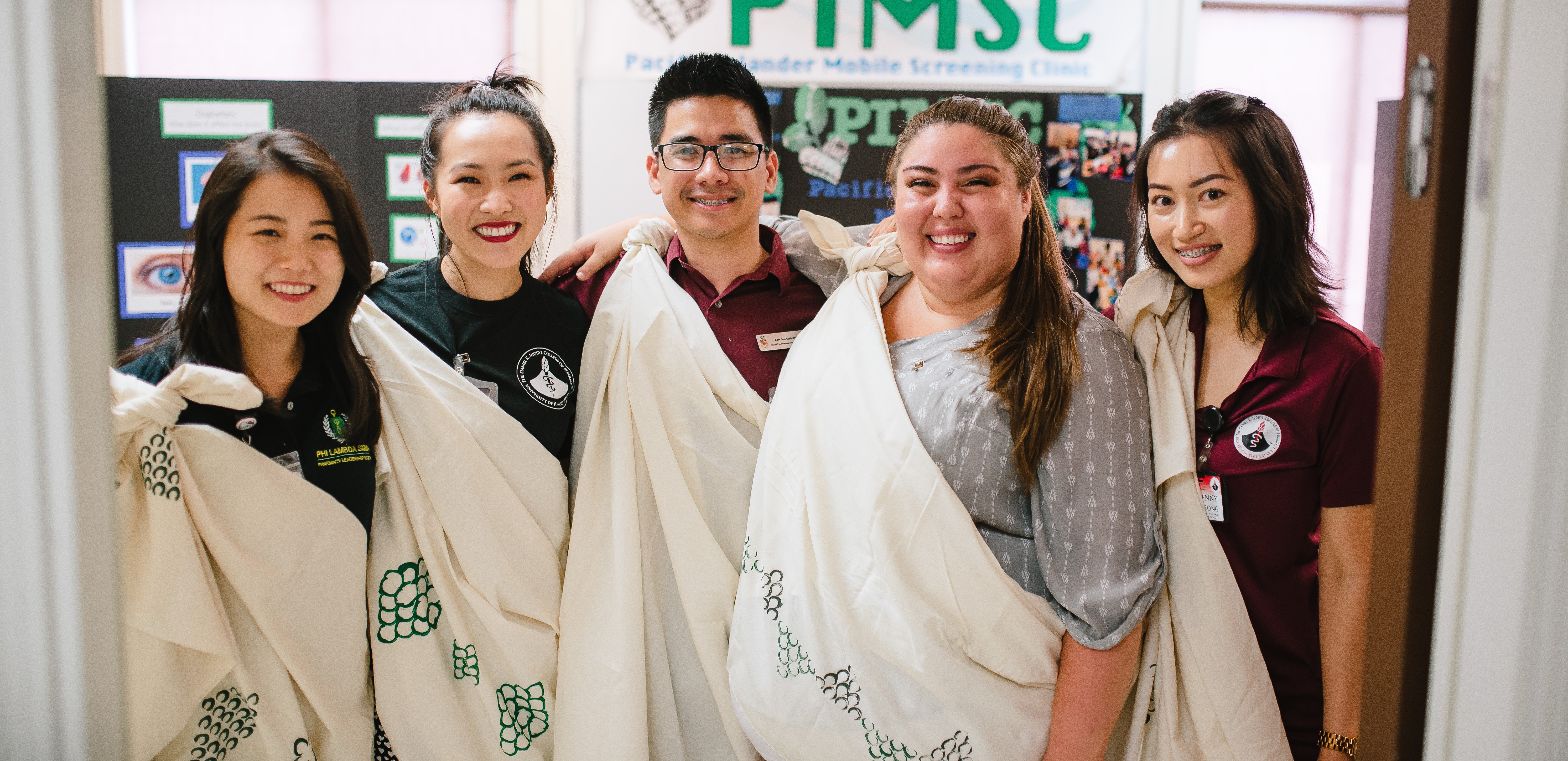Smiling students wearing kiheis, a traditional hawaiian wrap